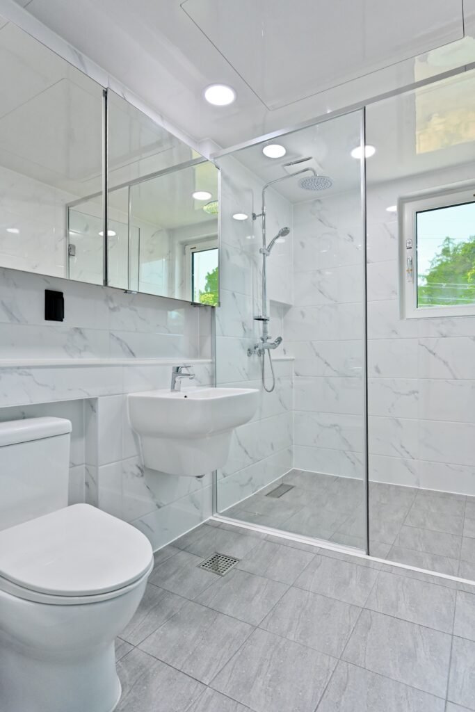 el espacio de la ducha se separa con una mampara de cristal en el bano decorado con azulejos bianco(1) el espacio de la ducha se separa con una mampara de cristal en el bano decorado con azulejos bianco(1)